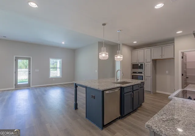 a kitchen with stainless steel appliances granite countertop a sink a stove a refrigerator and island with wooden floor