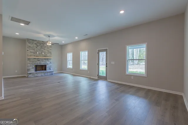 an empty room with wooden floor fireplace and windows