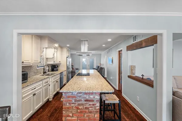a large kitchen with granite countertop a large counter top and stainless steel appliances