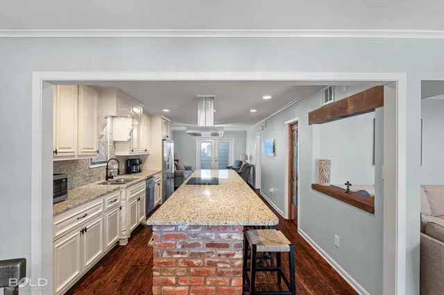 a large kitchen with granite countertop a large counter top and stainless steel appliances