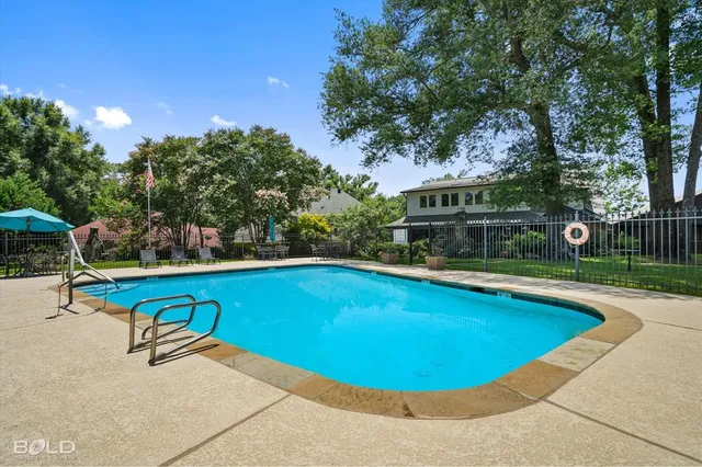 a view of a swimming pool with lounge chair and trees in the background