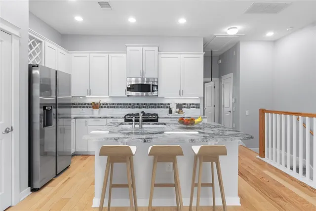 a kitchen with stainless steel appliances granite countertop a refrigerator and a stove top oven