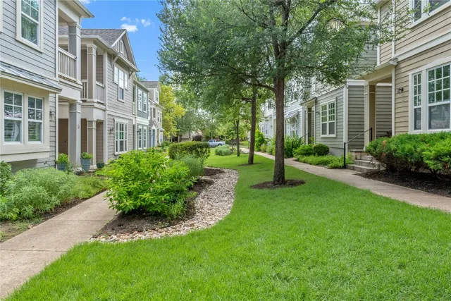 a view of a brick house with a yard and plants