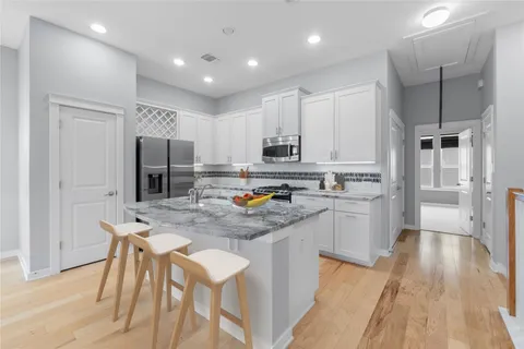 a kitchen with stainless steel appliances a refrigerator a stove a sink dishwasher and a refrigerator with wooden floor