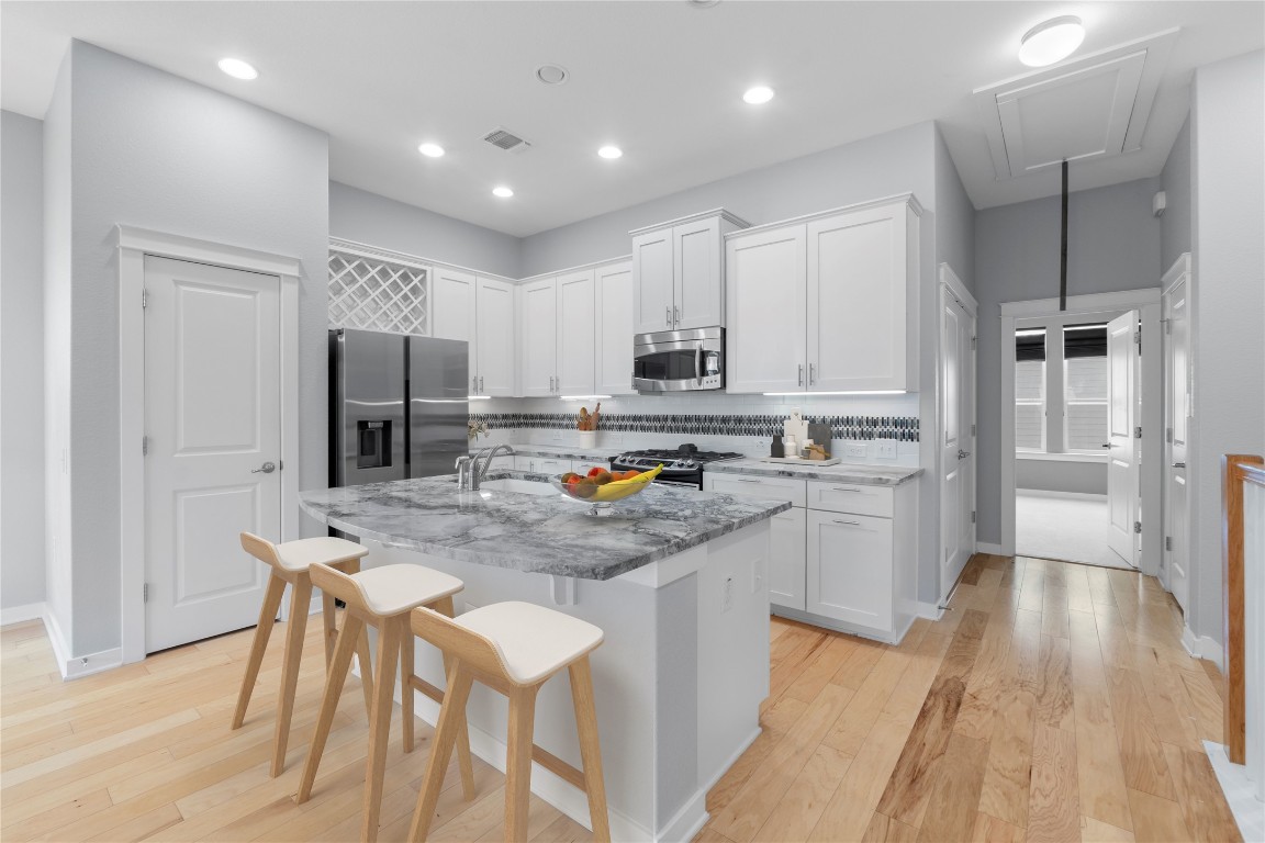 3900 Threadgill Street, Unit 16 Austin, TX 78723 - Photo 4 of 40 a kitchen with stainless steel appliances a refrigerator a stove a sink dishwasher and a refrigerator with wooden floor