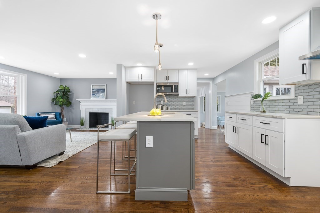 a kitchen with stainless steel appliances granite countertop a stove a sink dishwasher a refrigerator white cabinets with wooden floor