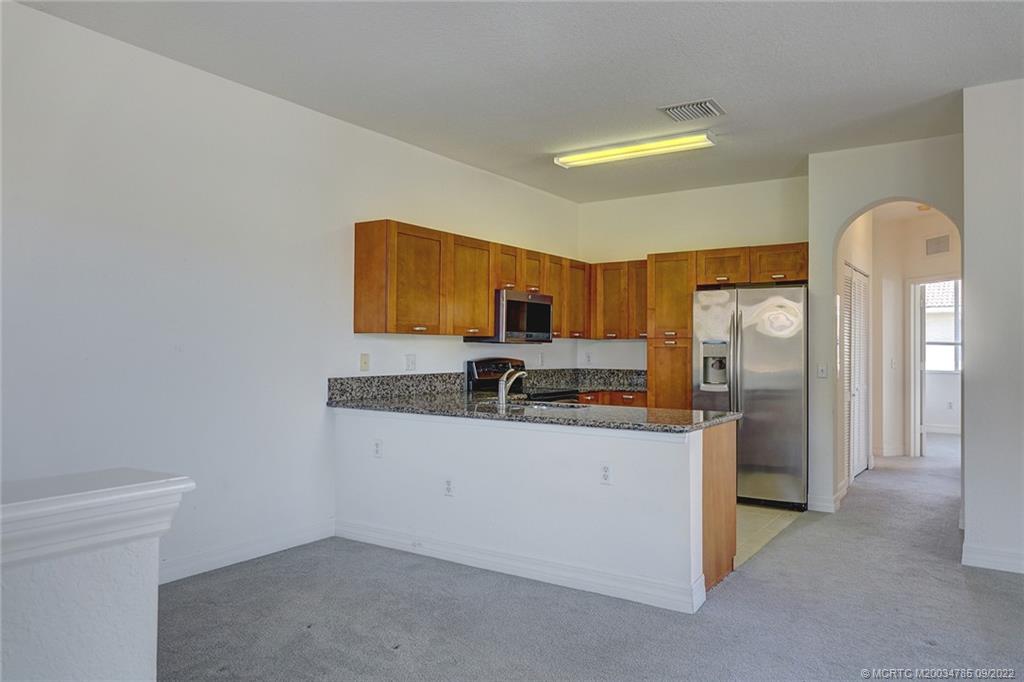63 Southeast Palermo, Unit 202 Stuart, FL 34994 - Photo 16 of 30 a kitchen with stainless steel appliances granite countertop a sink and a refrigerator
