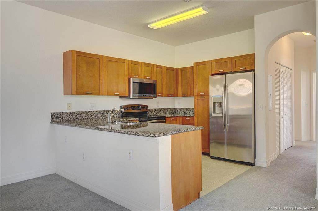 63 Southeast Palermo, Unit 202 Stuart, FL 34994 - Photo 18 of 30 a kitchen with stainless steel appliances granite countertop a refrigerator a stove a sink and a white cabinets