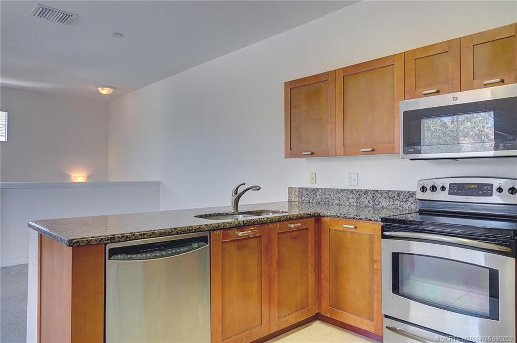63 Southeast Palermo, Unit 202 Stuart, FL 34994 - Photo 21 of 30 a kitchen with granite countertop a sink stove and cabinets
