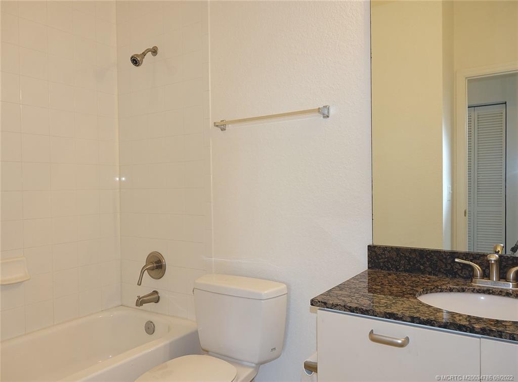 63 Southeast Palermo, Unit 202 Stuart, FL 34994 - Photo 26 of 30 a bathroom with a granite countertop sink a toilet and bathtub