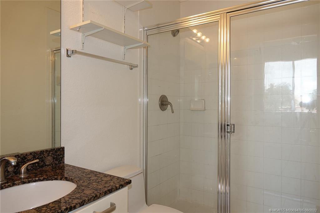 63 Southeast Palermo, Unit 202 Stuart, FL 34994 - Photo 28 of 30 a bathroom with a granite countertop shower and a sink