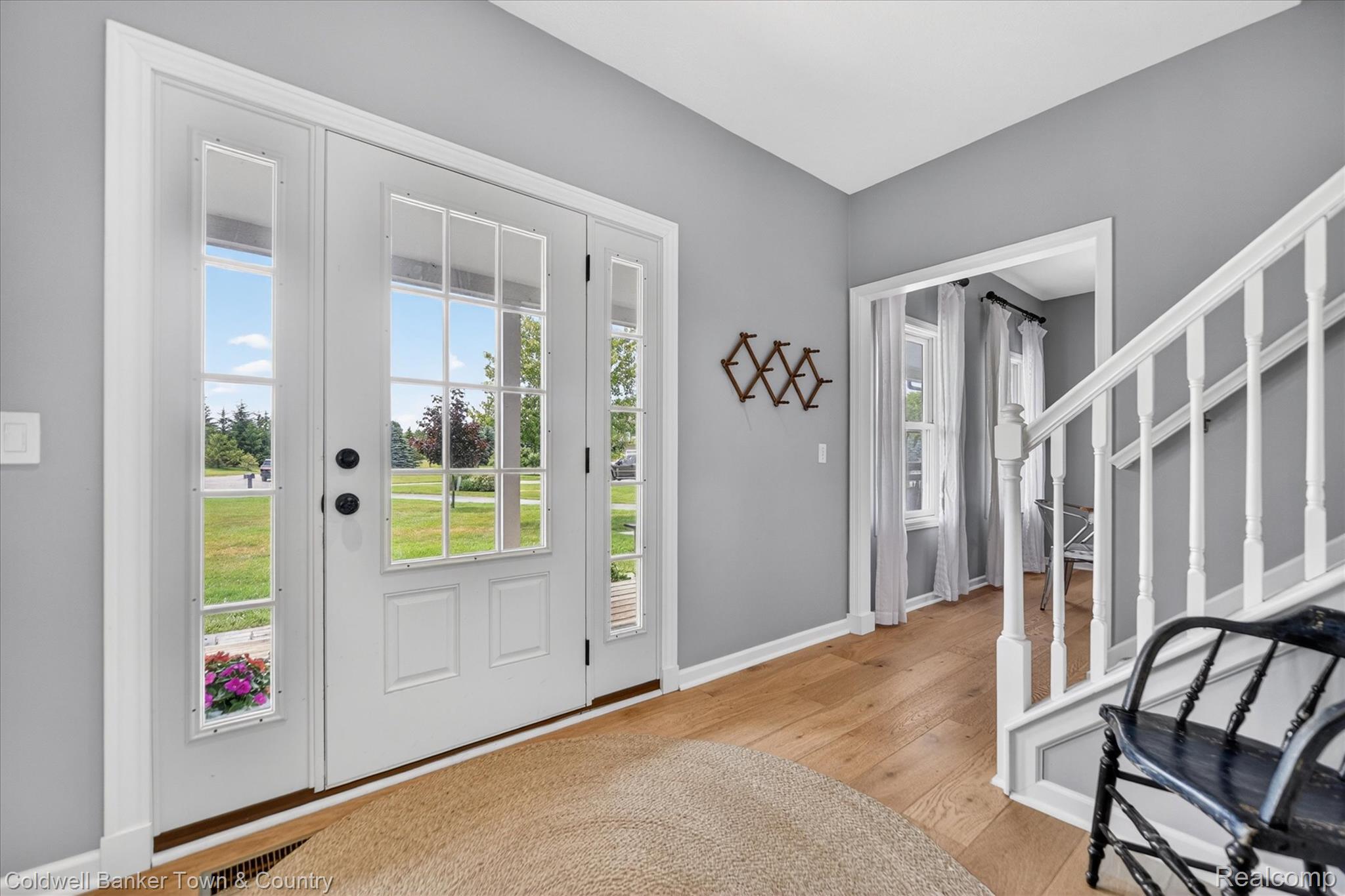 918 Gray Fox Court Howell, MI 48843 - Photo 8 of 84 Entryway featuring a white paneled door with sidelights, wood-finish flooring, light gray walls, and a white staircase with balusters