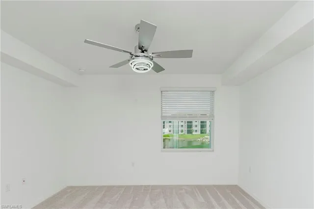 an empty room with a window and a fan