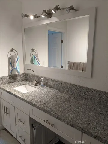 a bathroom with a granite countertop sink and a mirror