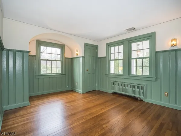 a view of an empty room with window and wooden floor