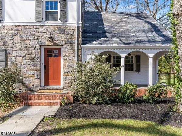 a front view of a house with lots of plants and wooden fence