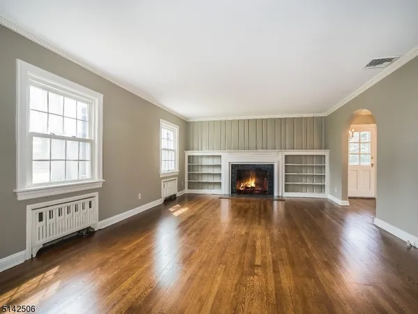 an empty room with wooden floor fireplace and windows