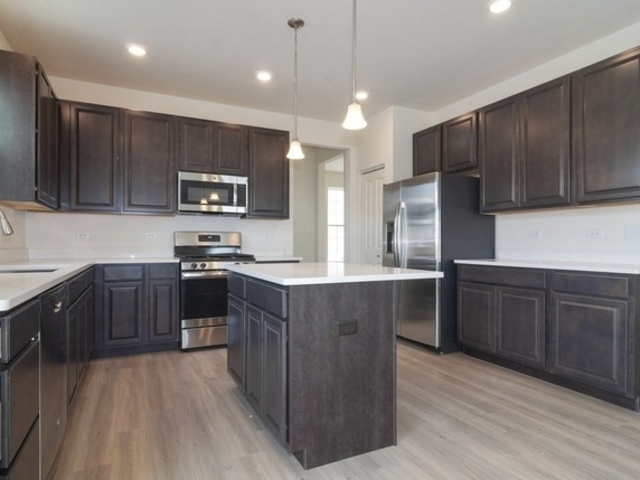 3118 Patterson Road Montgomery, IL 60538 - Photo 9 of 23 a kitchen with stainless steel appliances kitchen island granite countertop a stove a sink dishwasher a refrigerator and a oven with wooden floor