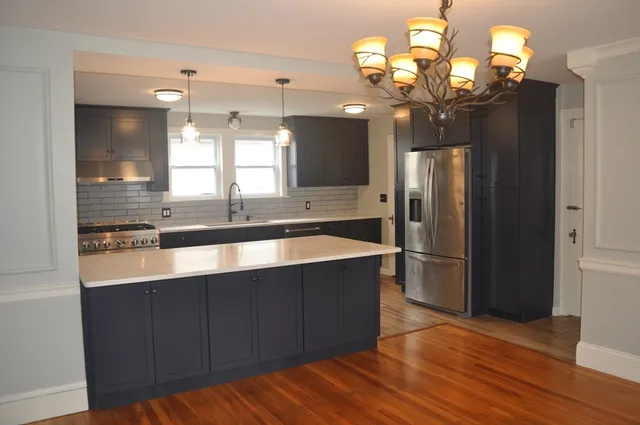 a kitchen with kitchen island granite countertop wooden floor and refrigerator