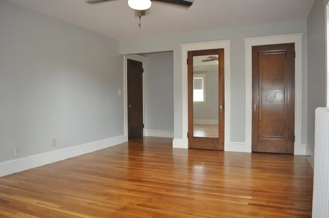 a view of an empty room with wooden floor and a window