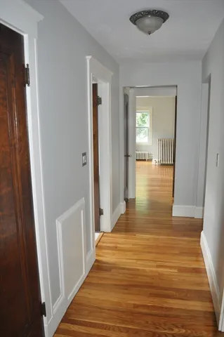 a view of a hallway with wooden floor and a bathroom