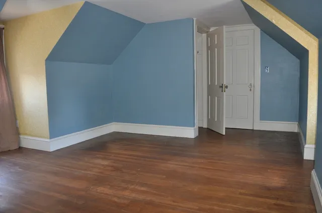 a view of an empty room with wooden floor and closet