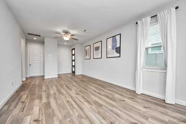 a view of empty room with wooden floor and fan