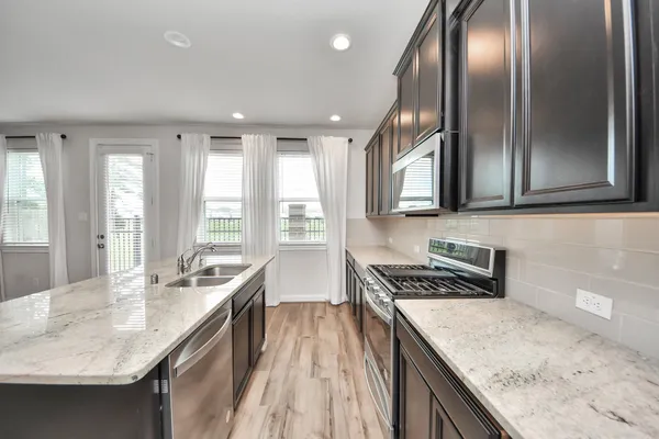 a kitchen with granite countertop stainless steel appliances window a sink and living room view