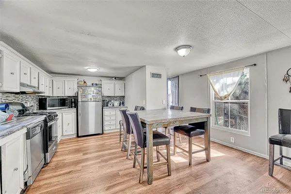 a kitchen with stainless steel appliances a dining table chairs stove refrigerator and cabinets