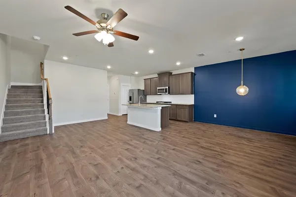 a view of kitchen with kitchen island stainless steel appliances refrigerator stove microwave and white cabinets