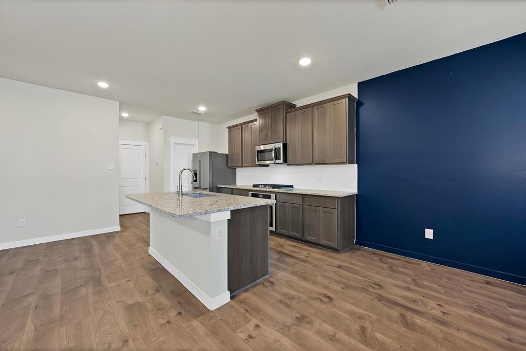 6610 Baritone Court Sachse, TX 75048 - Photo 6 of 30 a kitchen with stainless steel appliances granite countertop a stove a sink and a refrigerator with wooden floor