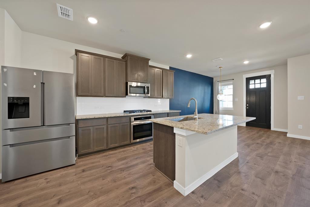 6610 Baritone Court Sachse, TX 75048 - Photo 7 of 30 a kitchen with stainless steel appliances and white cabinets