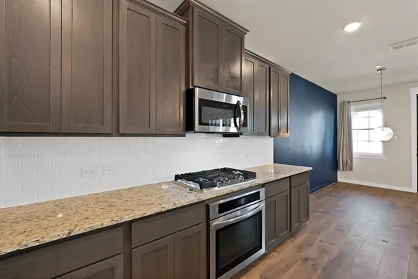 a kitchen with granite countertop cabinets stainless steel appliances and wooden floor