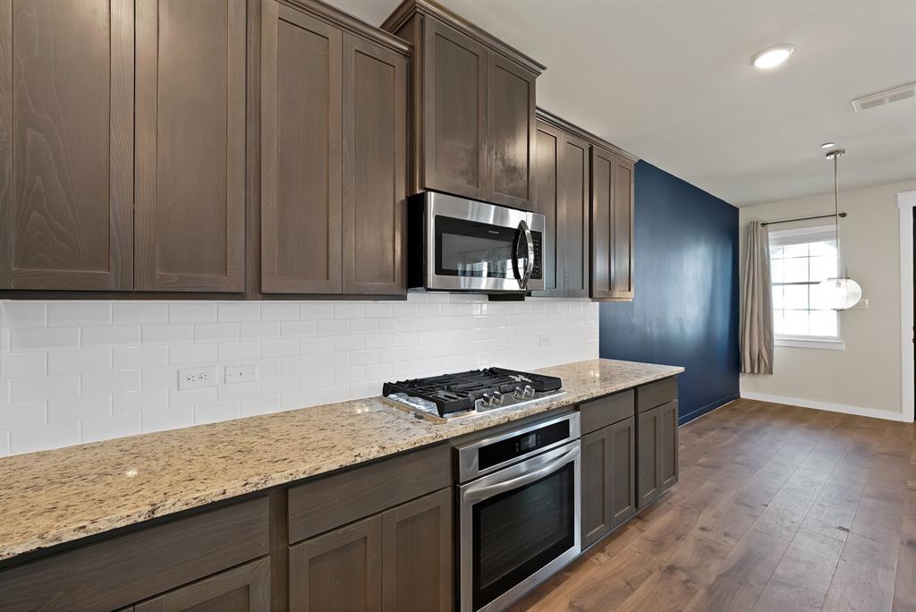 6610 Baritone Court Sachse, TX 75048 - Photo 8 of 30 a kitchen with granite countertop cabinets stainless steel appliances and wooden floor