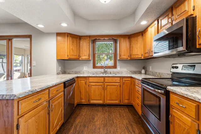 a kitchen with stainless steel appliances granite countertop wooden floor sink stove and microwave