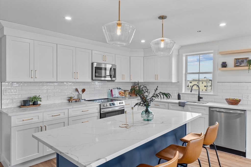 30 Cable Avenue, Unit 3 Salisbury, MA 01952 - Photo 9 of 31 a kitchen with stainless steel appliances kitchen island granite countertop a sink a stove a microwave a dining table and chairs