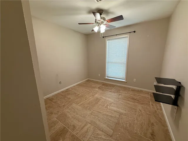an empty room with a chandelier fan and a window