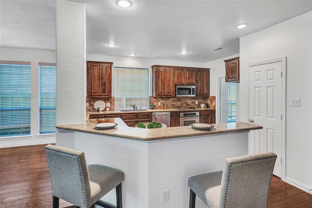1504 Tangle Ridge Drive McKinney, TX 75071 - Photo 13 of 36 a kitchen with stainless steel appliances a sink and a stove