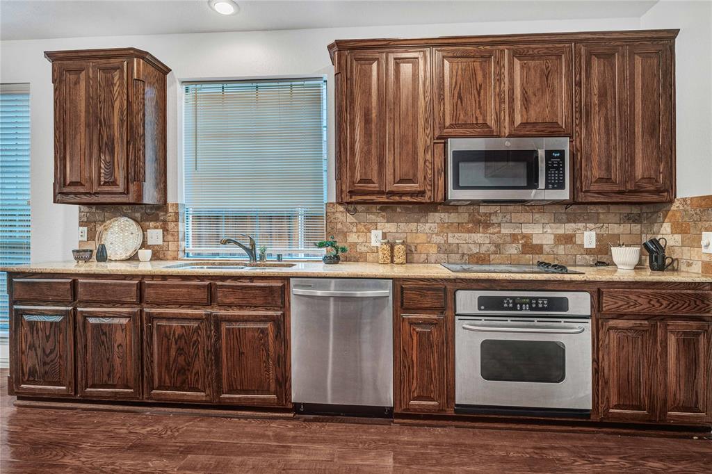 1504 Tangle Ridge Drive McKinney, TX 75071 - Photo 15 of 36 a kitchen with granite countertop wood cabinets stainless steel appliances and a sink