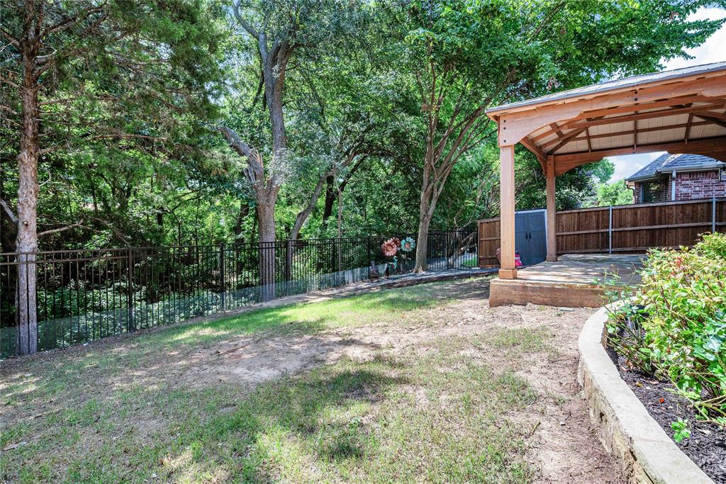 1504 Tangle Ridge Drive McKinney, TX 75071 - Photo 33 of 36 a backyard of a house with large trees and plants