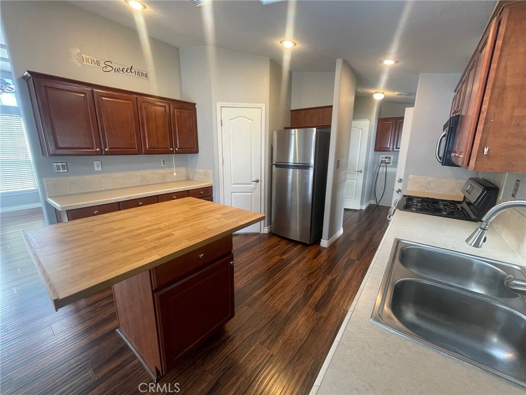 15181 Van Buren Boulevard, Unit 22 Riverside, CA 92504 - Photo 18 of 61 a kitchen with stainless steel appliances granite countertop a stove a refrigerator and a sink with wooden floor