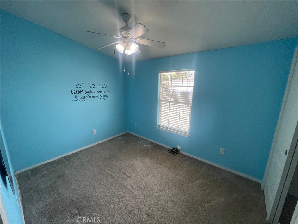 15181 Van Buren Boulevard, Unit 22 Riverside, CA 92504 - Photo 29 of 61 an empty room with a chandelier fan and windows
