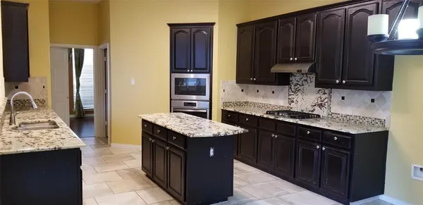 a kitchen with granite countertop a sink stove and cabinets