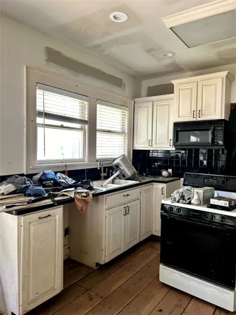 a kitchen with kitchen island granite countertop a sink wooden floor cabinets and a window