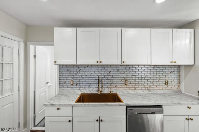 a kitchen with white cabinets a sink and dishwasher