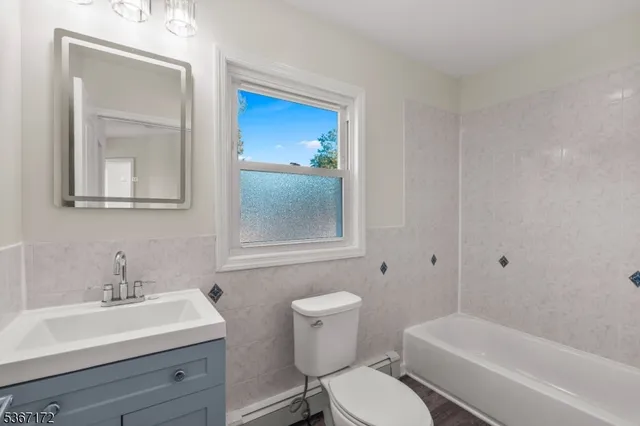 a bathroom with a toilet a sink a mirror and vanity