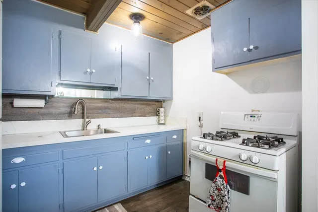 a kitchen with granite countertop a sink stove and cabinets