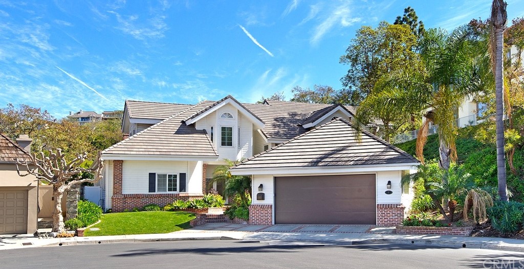 a view of a white house with a small yard and large tree