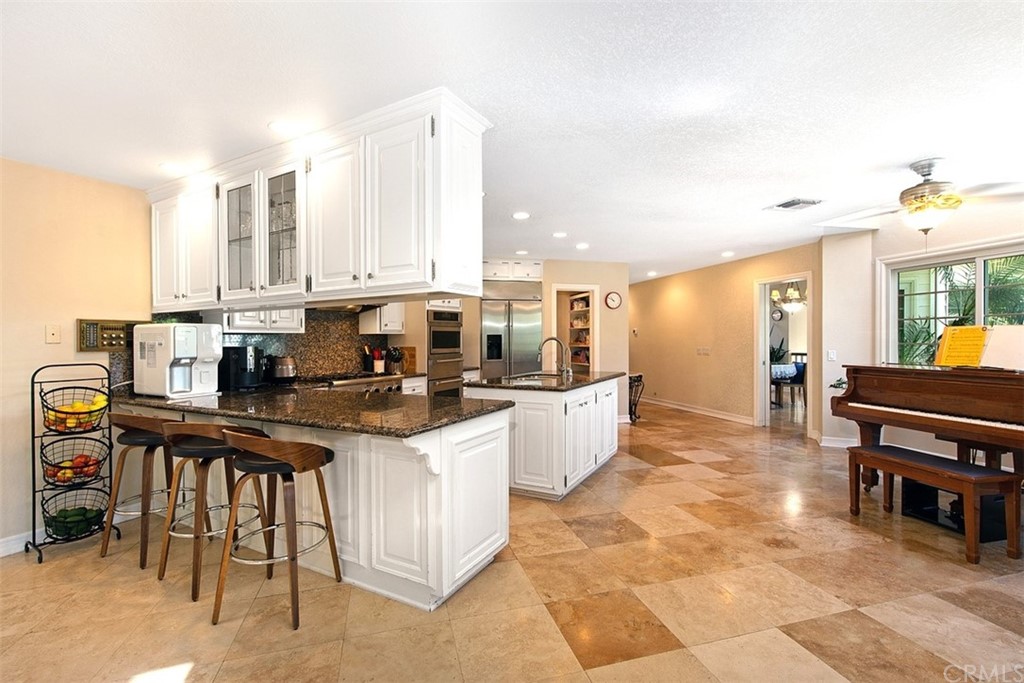 7 Windsor Newport Beach, CA 92660 - Photo 11 of 40 a kitchen with stainless steel appliances kitchen island granite countertop a table and chairs