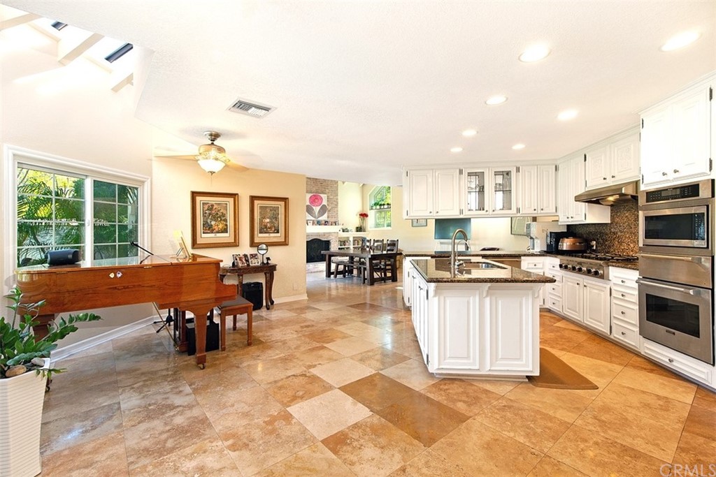 7 Windsor Newport Beach, CA 92660 - Photo 10 of 40 a kitchen with stainless steel appliances kitchen island granite countertop a refrigerator a stove a sink and a dining table with wooden floor